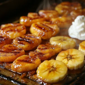 A close-up of caramelized bananas, grilled peaches, and pineapple slices cooking on a flat-top griddle. The bananas have a golden-brown glaze, and the peaches have distinct grill marks. Honey drizzled over the fruit, with cinnamon dusting and a scoop of vanilla yogurt on the side. Steam rising, ultra-realistic textures, high detail, professional food photography, warm and inviting morning ambiance.